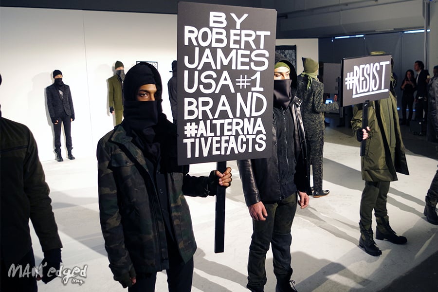 A shot showcasing various models holding political signage at men's fashion week.