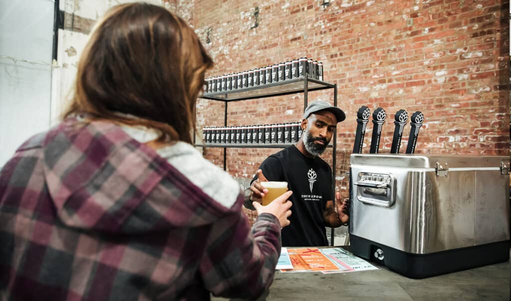 Bartender passing out the Lace 'Em Up Lager beer created by Wolverine and Torch & Crown brewery.