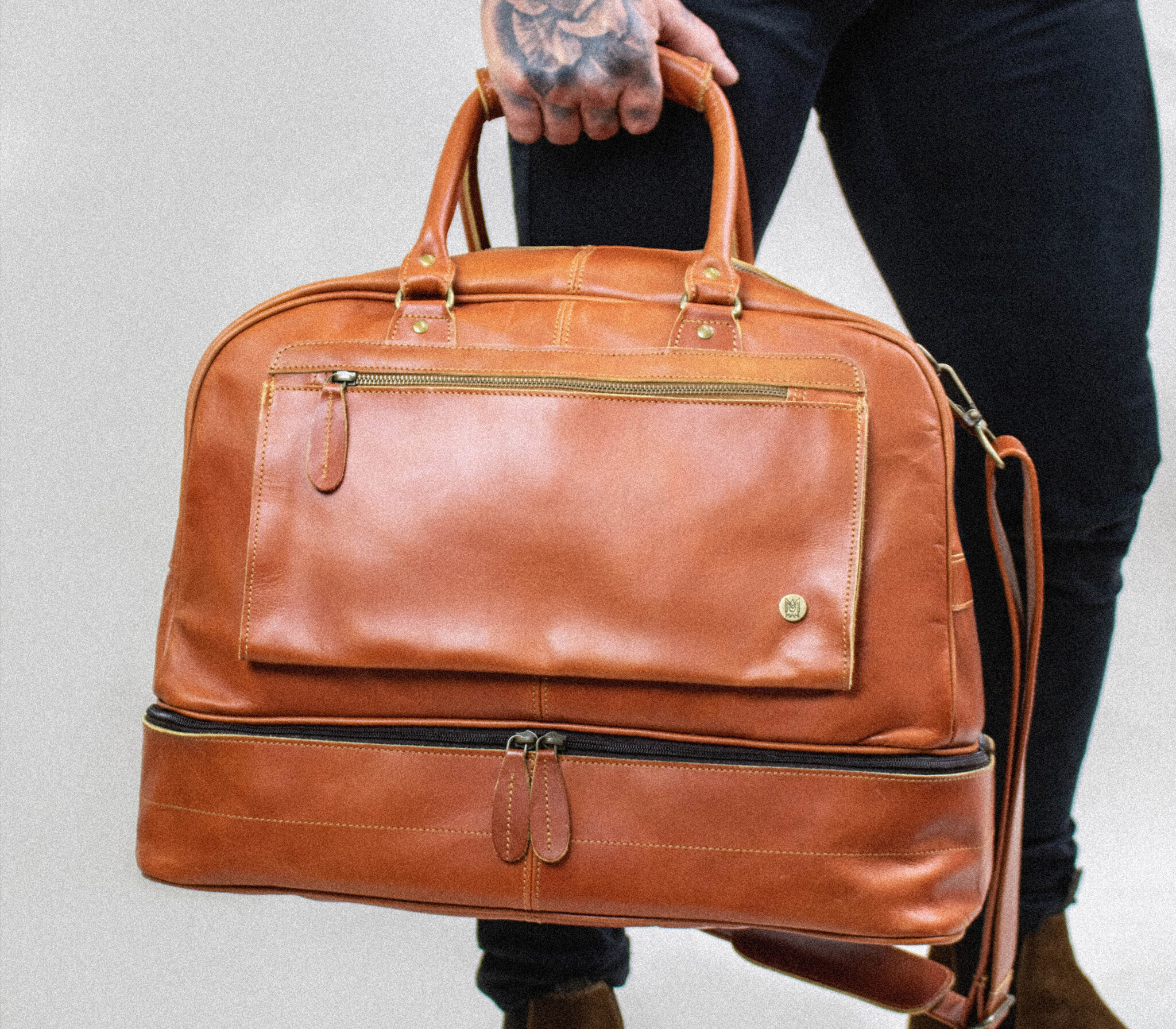 man holding a tan men's travel bag