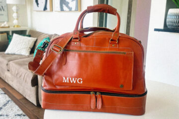 michael william g's embroidered men's travel bag in tan color sitting on table