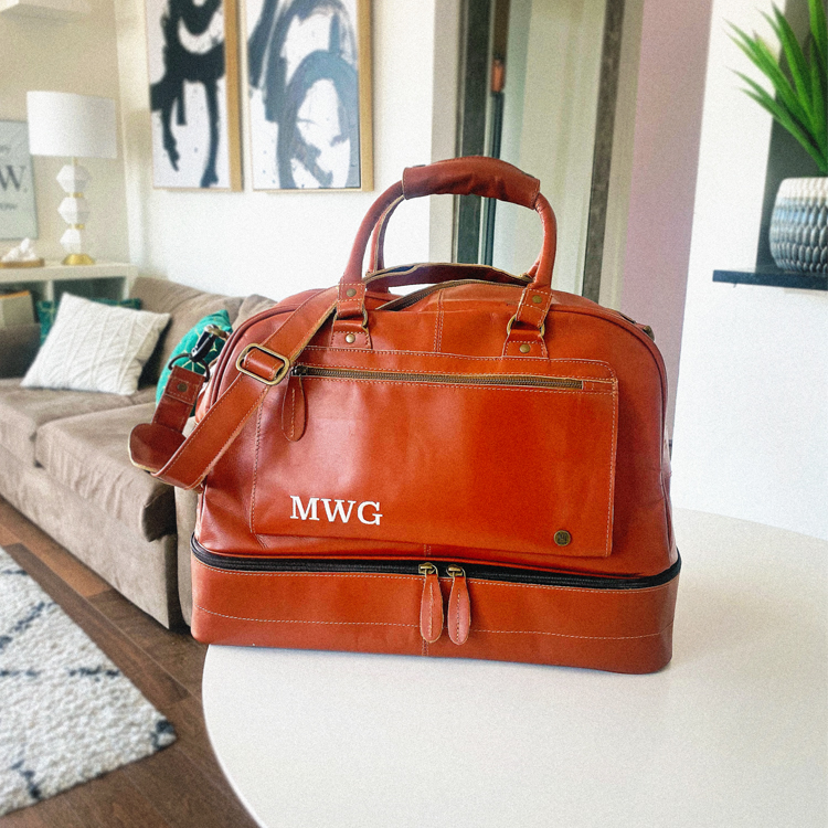 michael william g's embroidered men's travel bag in tan color sitting on table