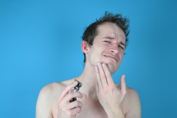 A man with sensitive skin who just got out of the shower is in pain after shaving with a razor the wrong way.