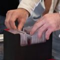 A man thumbing through a black plastic container full of cover-protected collectible sports cards.