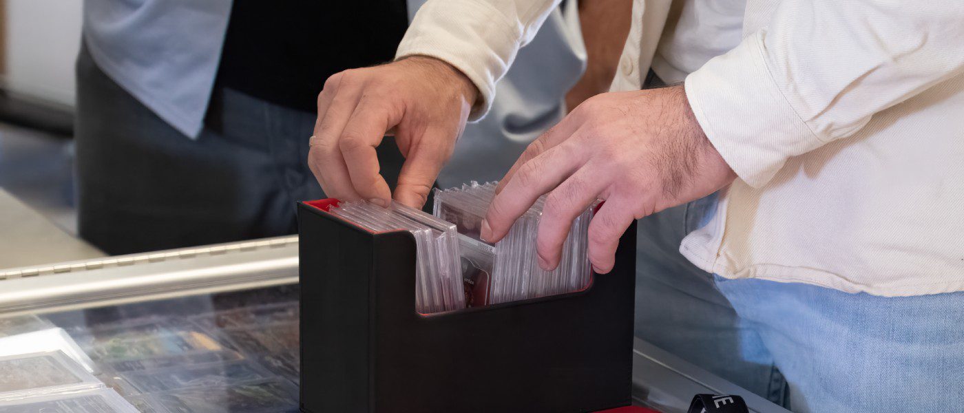 A man thumbing through a black plastic container full of cover-protected collectible sports cards.