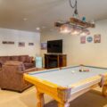 A classic man cave complete with comfortable furniture, game tables, entertainment systems, and various sporting décor.