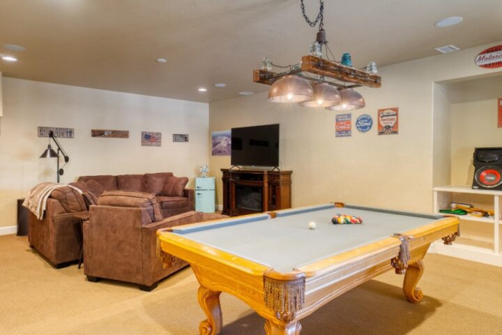 A classic man cave complete with comfortable furniture, game tables, entertainment systems, and various sporting décor.