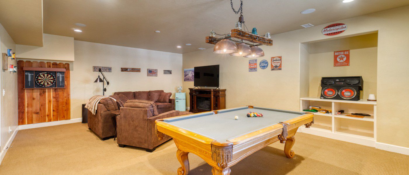 A classic man cave complete with comfortable furniture, game tables, entertainment systems, and various sporting décor.