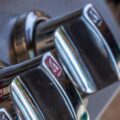 Close-up side view of three knobs on a gas grill. The grill lid is closed, and the grill's metal gleams.