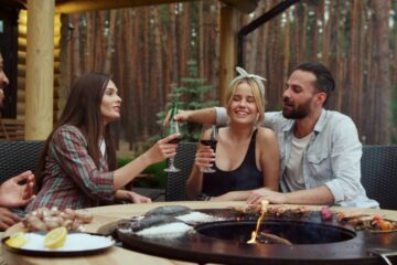 A group of friends gathered around an above-ground fire pit. They're socializing and enjoying beverages.