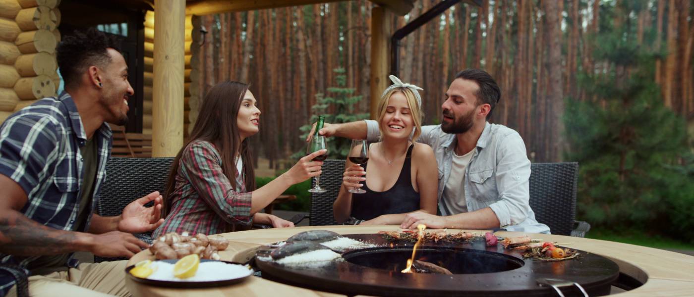 A group of friends gathered around an above-ground fire pit. They're socializing and enjoying beverages.