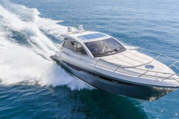 A blue and white luxury motorboat racing through a large body of water and leaving a wake behind it.