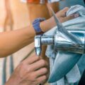 A close-up of a person with a blue watch using a cloth and a torque wrench on the propeller of a boat out of water.