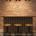 An interior of a modern home or apartment with a small bar and three stools lined up near a couch and fridge.