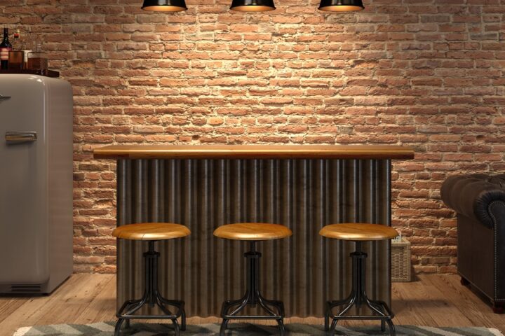 An interior of a modern home or apartment with a small bar and three stools lined up near a couch and fridge.