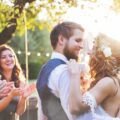 A bride and groom dancing outdoors at a wedding reception while seated guests watch from decorated tables.