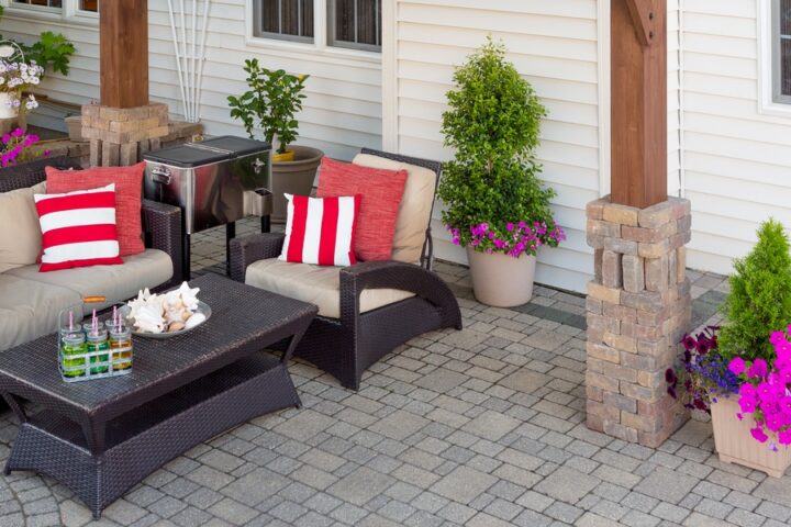 A close-up of a backyard space with a covered patio. There are lights hanging from above and seating around a low table.